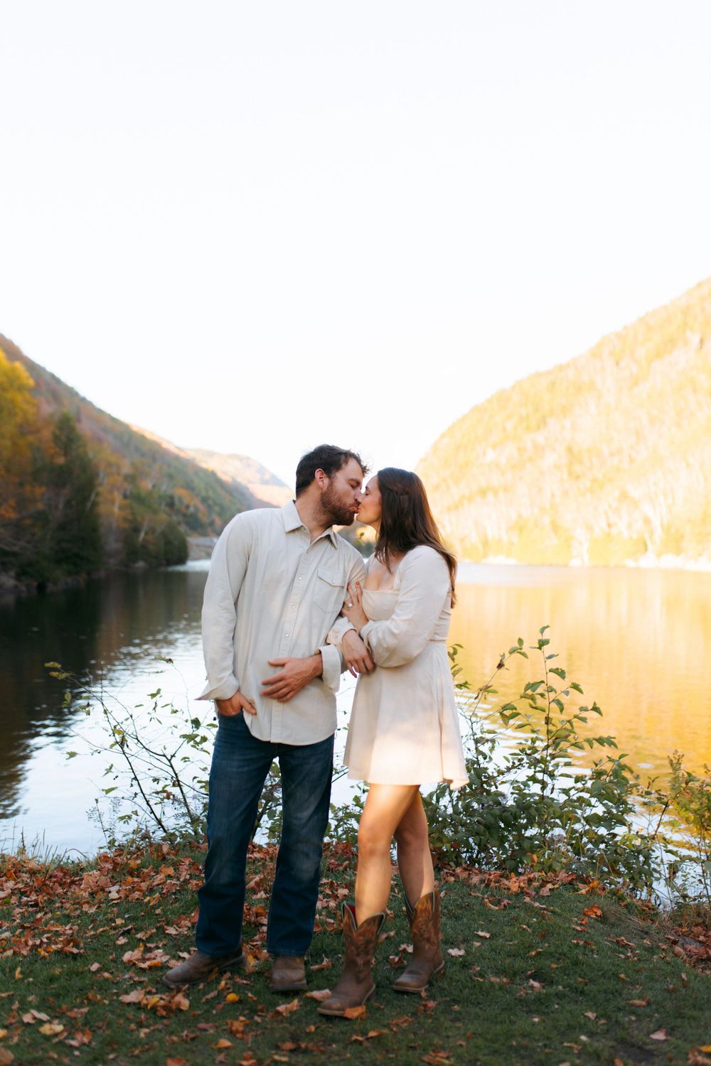 Romantic couple shares intimate moments by a scenic lake during golden hour sunset.