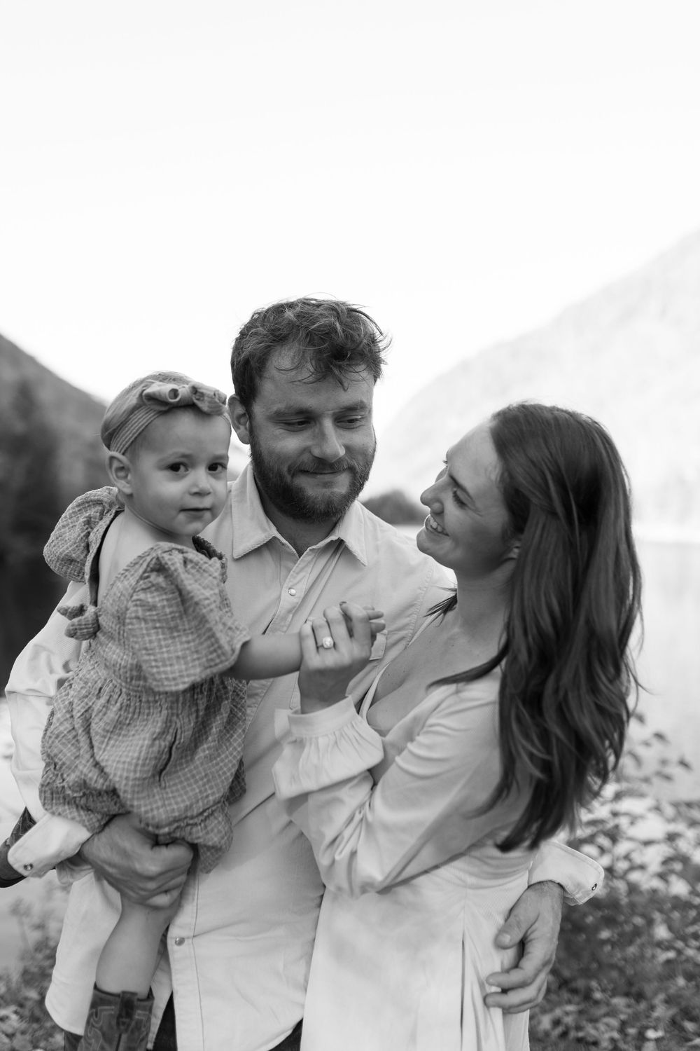 A family shares joyful moments together in a series of black and white outdoor portraits.