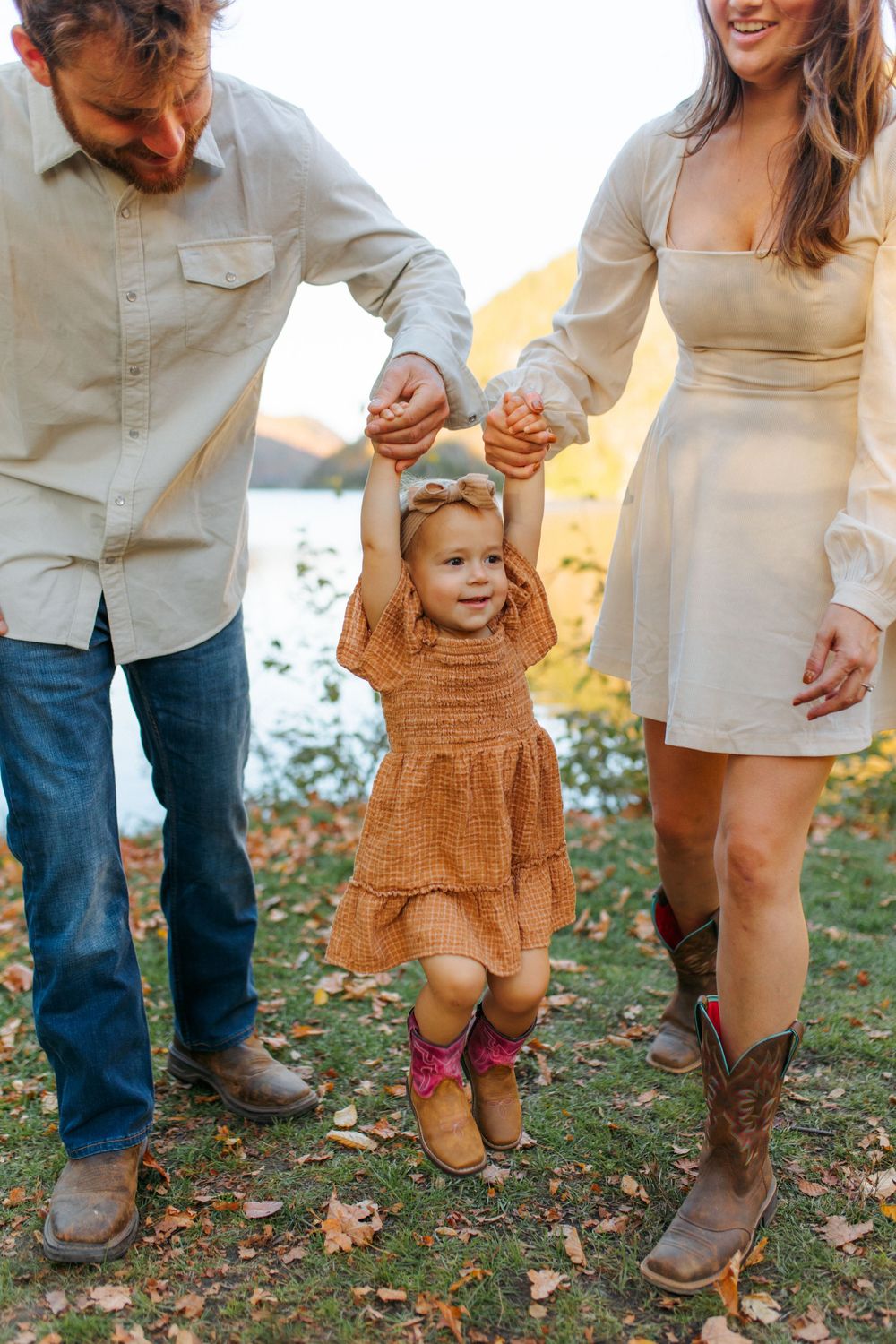 Series of photos showing parents helping toddler in orange dress take first steps on autumn grass.