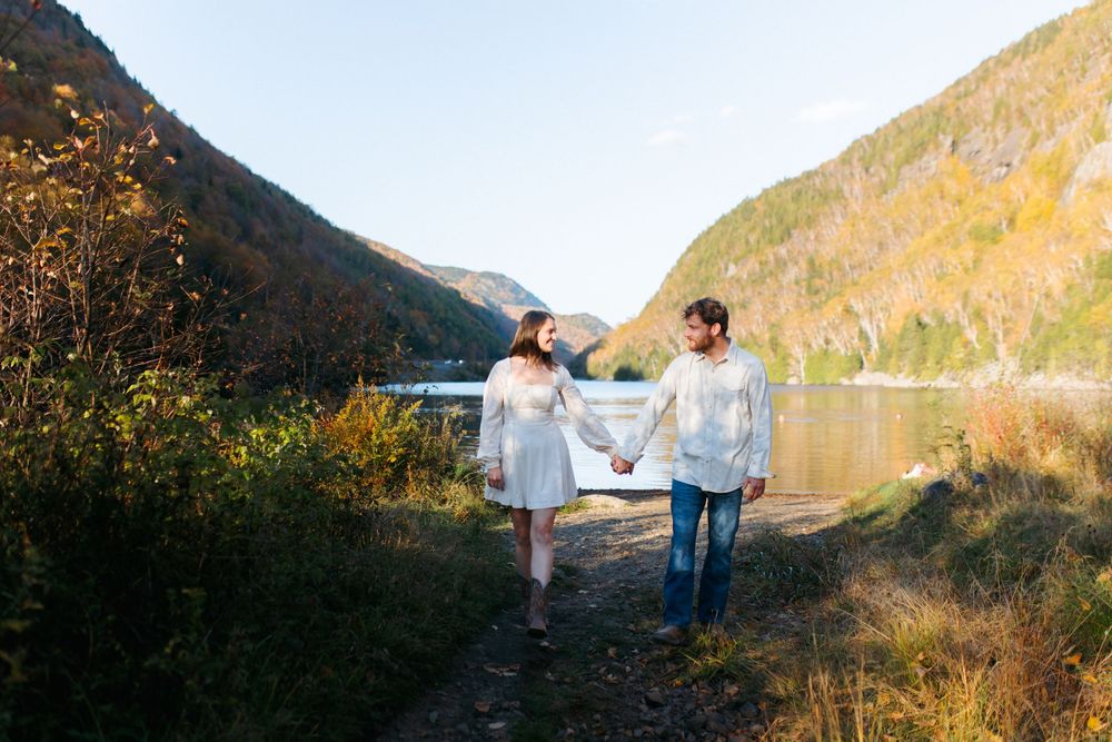 Dancing couple enjoying a tender moment on a lakeside path surrounded by autumn mountains.