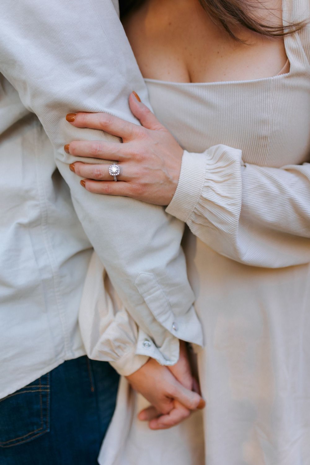 Close-up view of hands wearing a white ruffled sleeve blouse and blue jeans in a minimalist style.