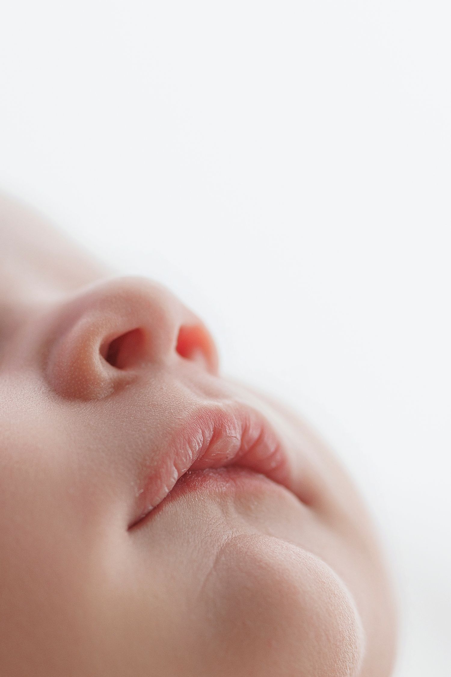 Close-up macro shot of a sleeping baby's nose and lips against a white background.