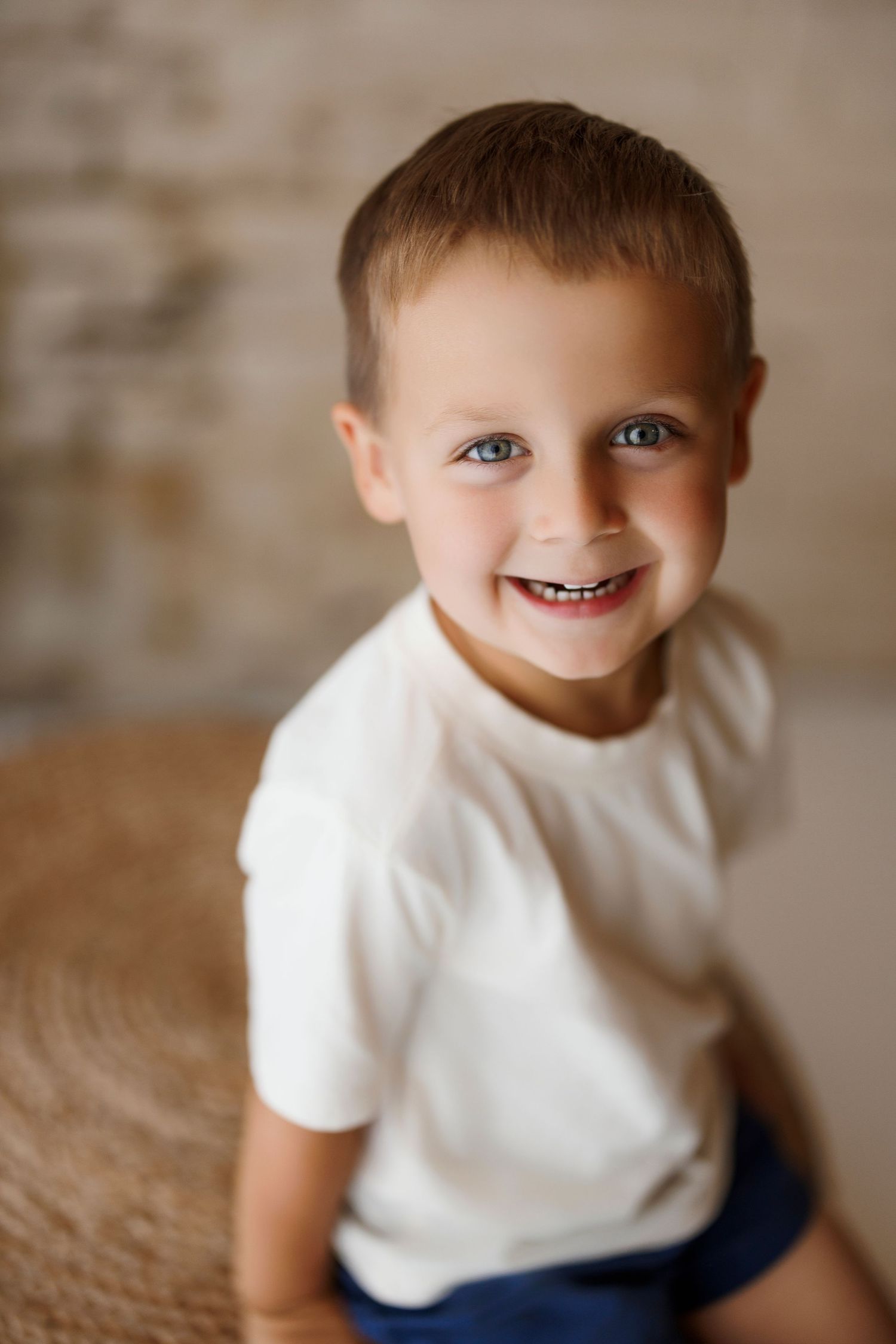A series of candid portrait shots showing a joyful child in a white t-shirt against a neutral background.
