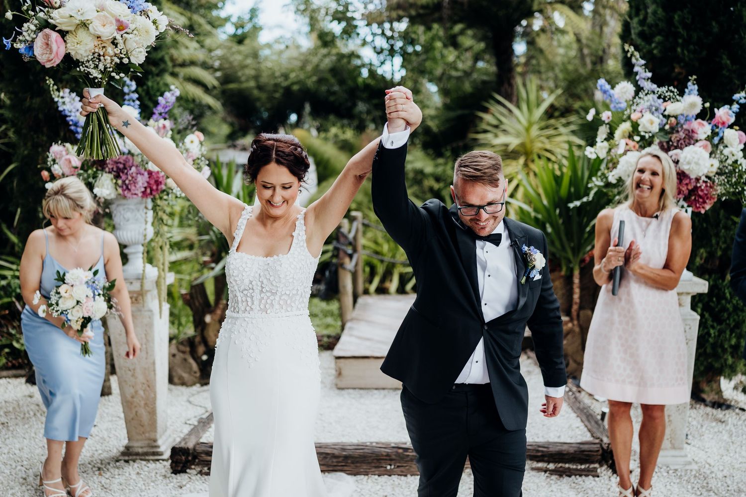 Wedding guests toss colorful confetti in celebration during an outdoor ceremony.