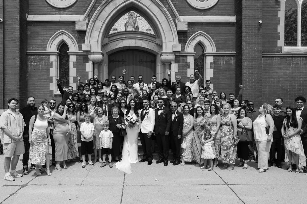 Large vintage group wedding photo on church steps with guests in formal 1920s attire gathered outside Gothic arches.