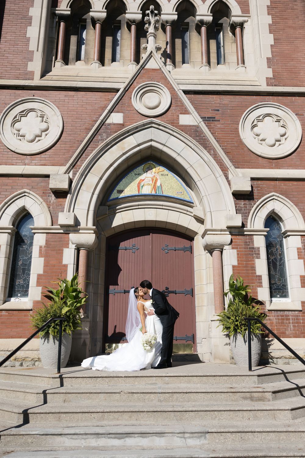 Wedding couple poses in front of a Gothic church entrance with arched doorways and ornate architectural details.