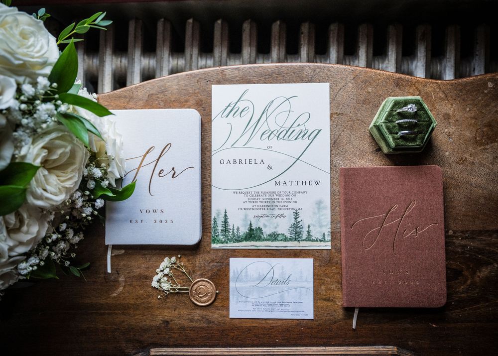 Wedding stationery suite with white roses and green accents on wooden surface.