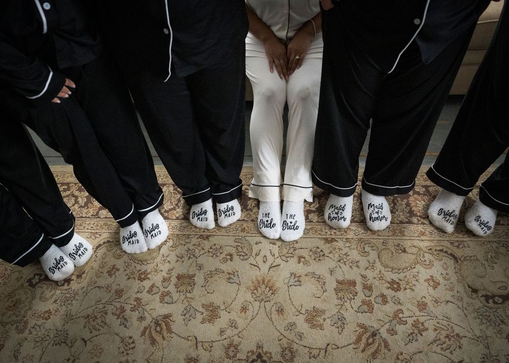 Wedding party members showing off their matching custom white Converse sneakers on a patterned carpet.