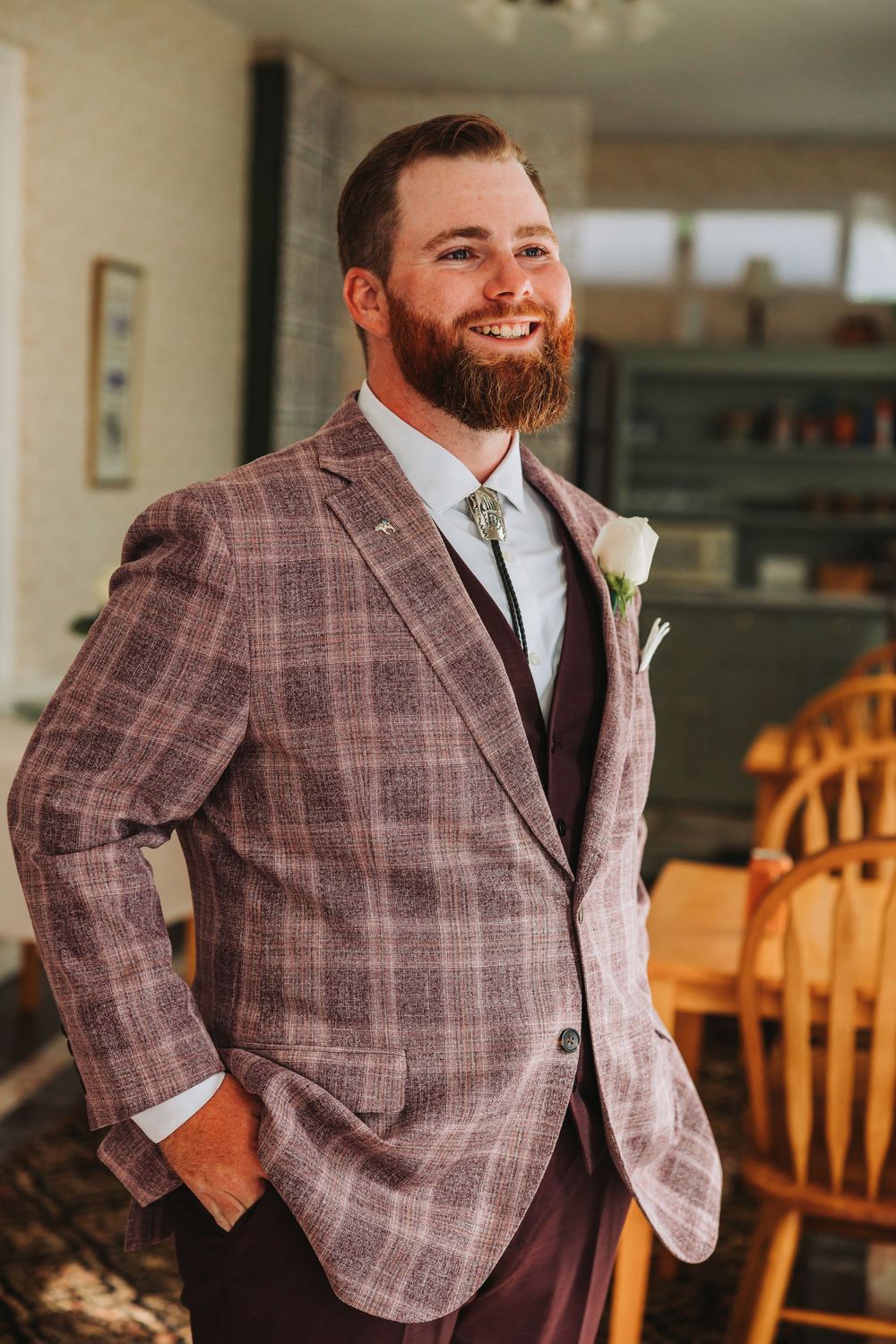 A person wearing a brown plaid blazer and white dress shirt poses in different angles in an indoor setting.