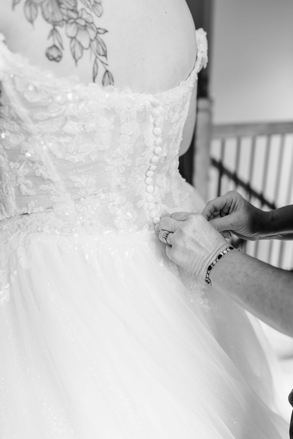 Close-up details of an ornate white lace wedding dress being fitted.