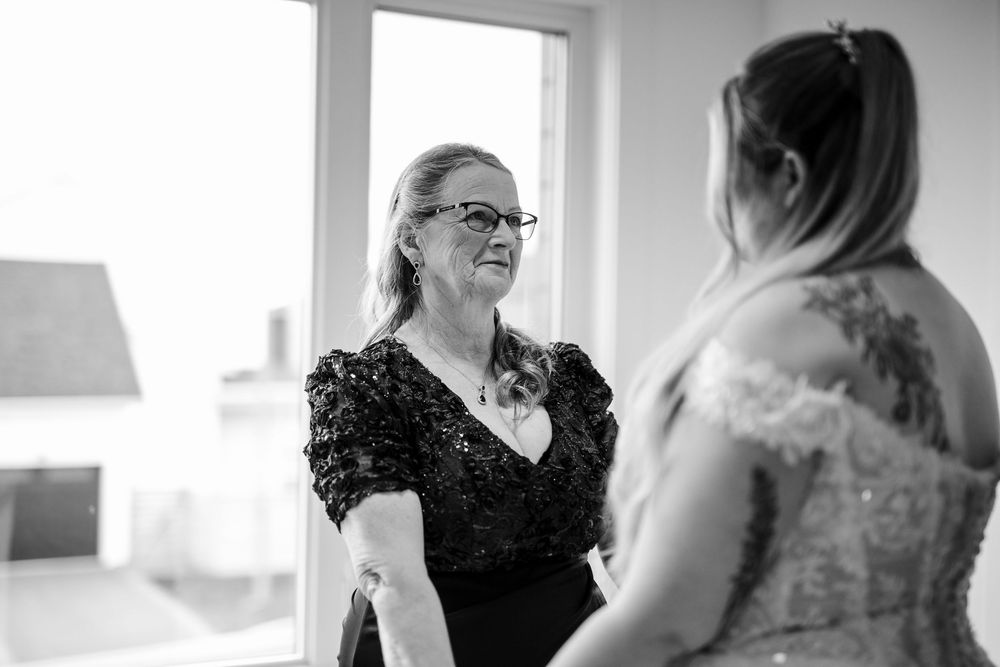 A monochrome image capturing an intimate pre-wedding moment with soft natural light streaming through windows.