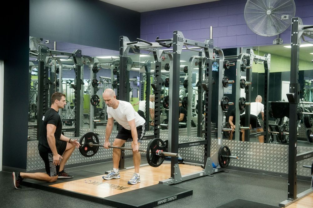 Modern fitness facility with weight equipment and wall-length mirrors.