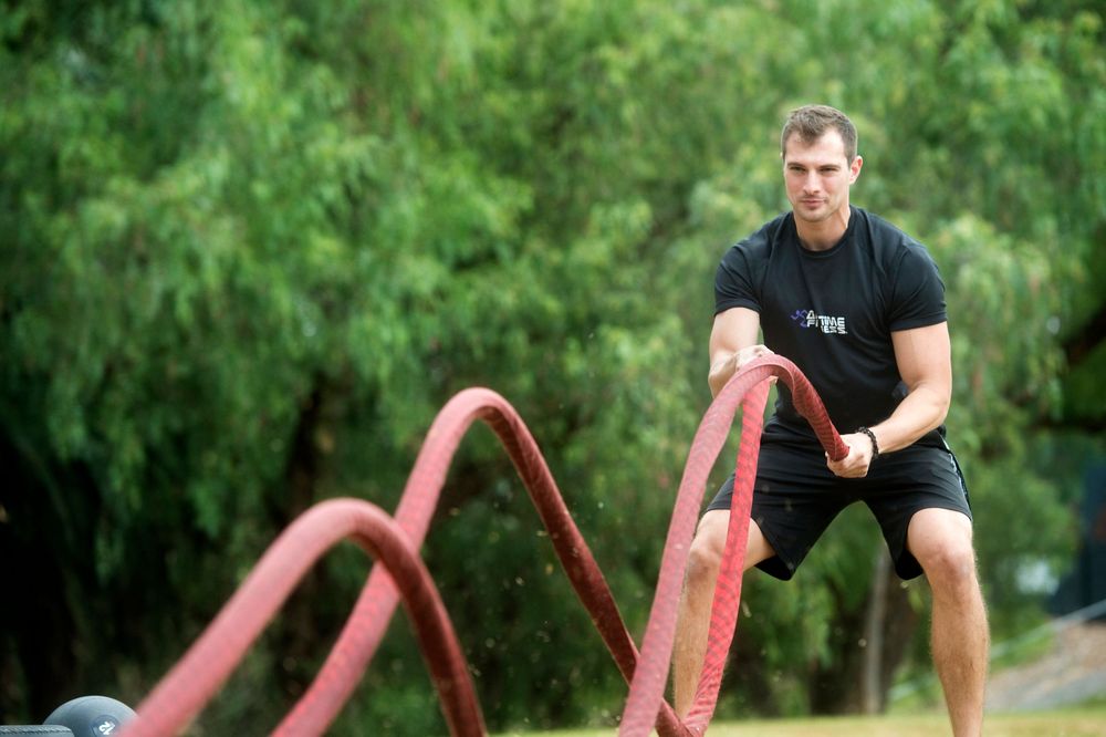 Outdoor fitness training session on red exercise equipment in park setting.