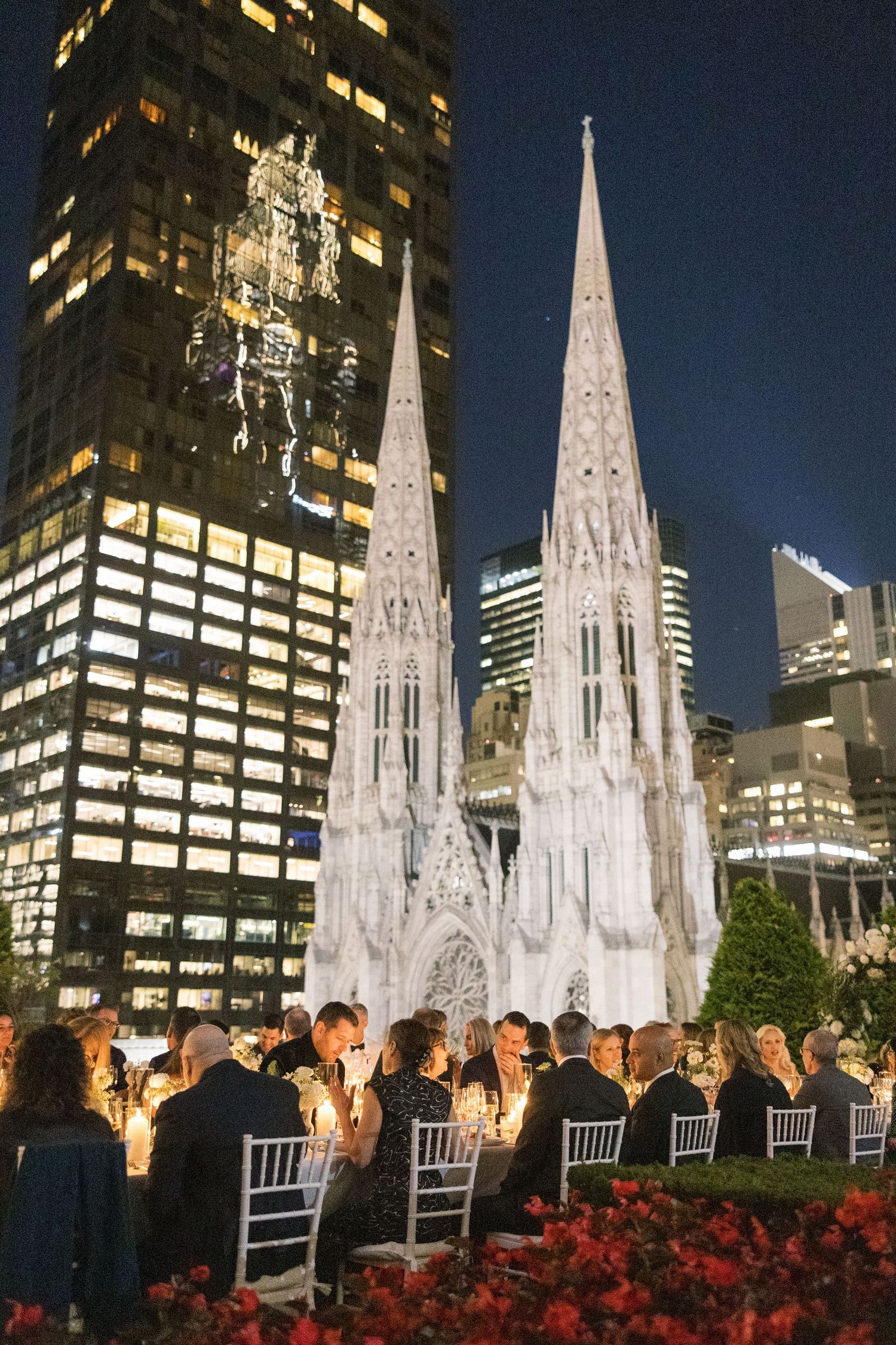 Nighttime rooftop reception with illuminated cathedral spires creating a dramatic backdrop.