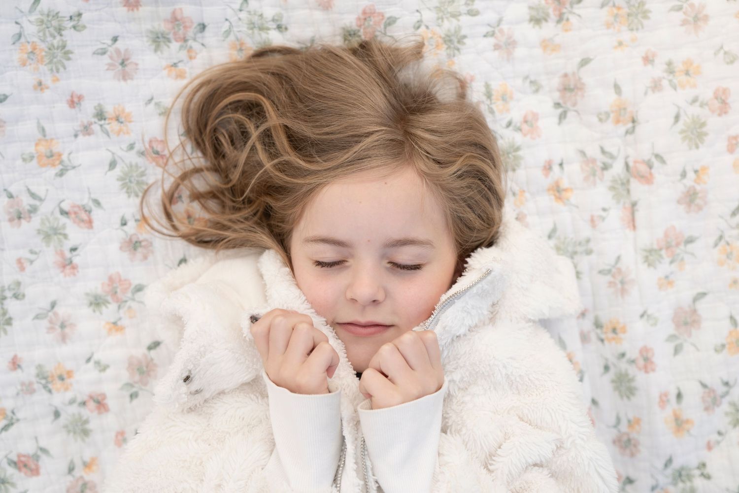 A series of dreamy photographs showing someone sleeping peacefully against floral wallpaper in soft, natural light.