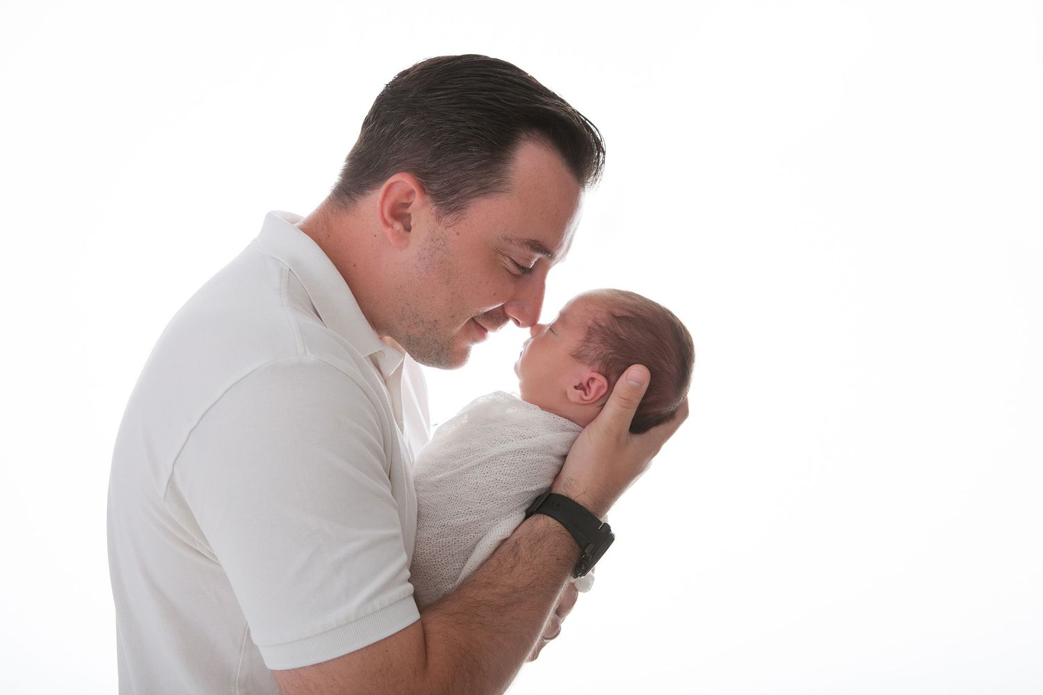 Person in white shirt expressing deep emotion with hands covering face against light background.