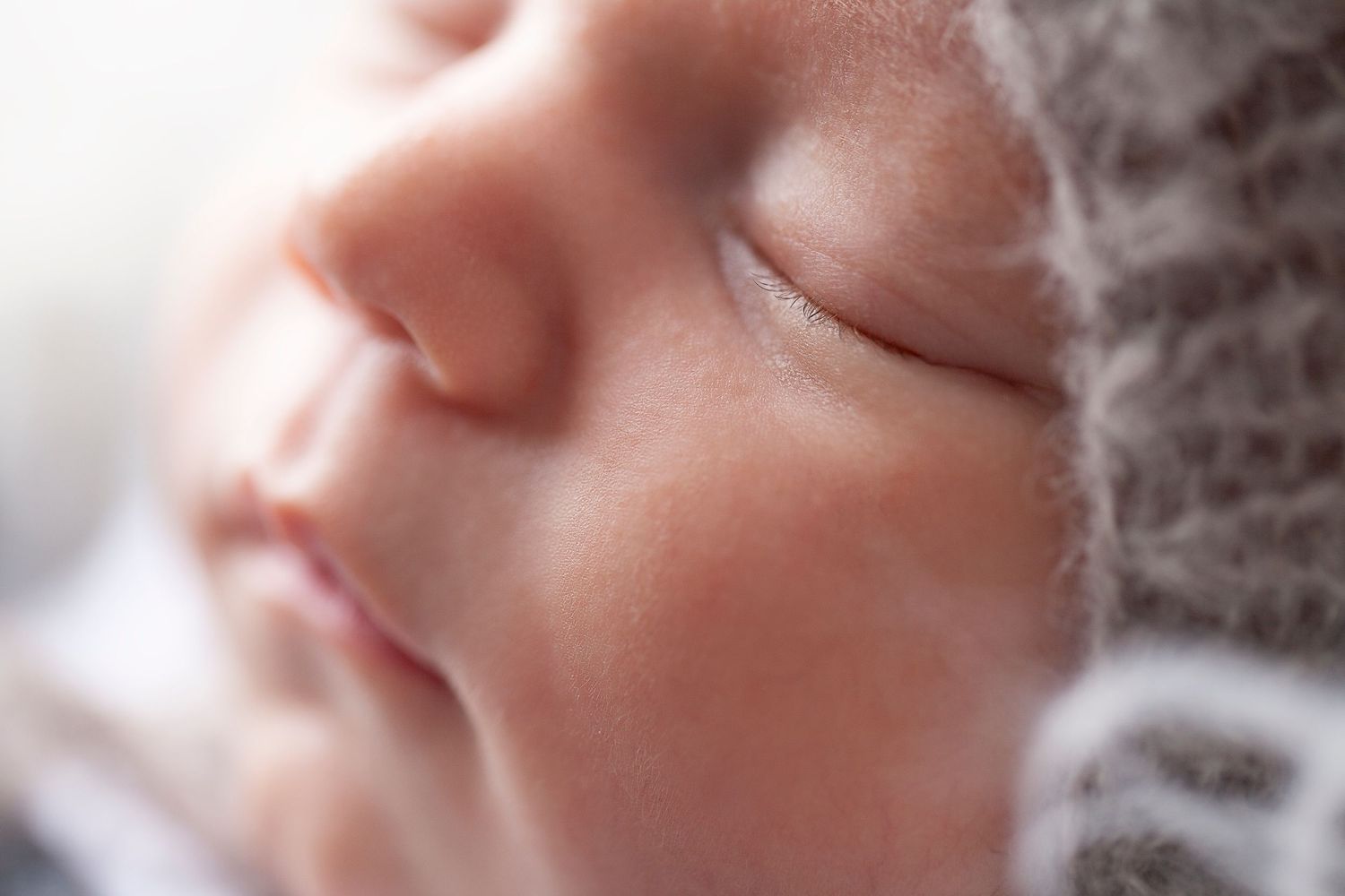 A close-up macro shot shows a peaceful sleeping baby's face wrapped in soft knit fabric.
