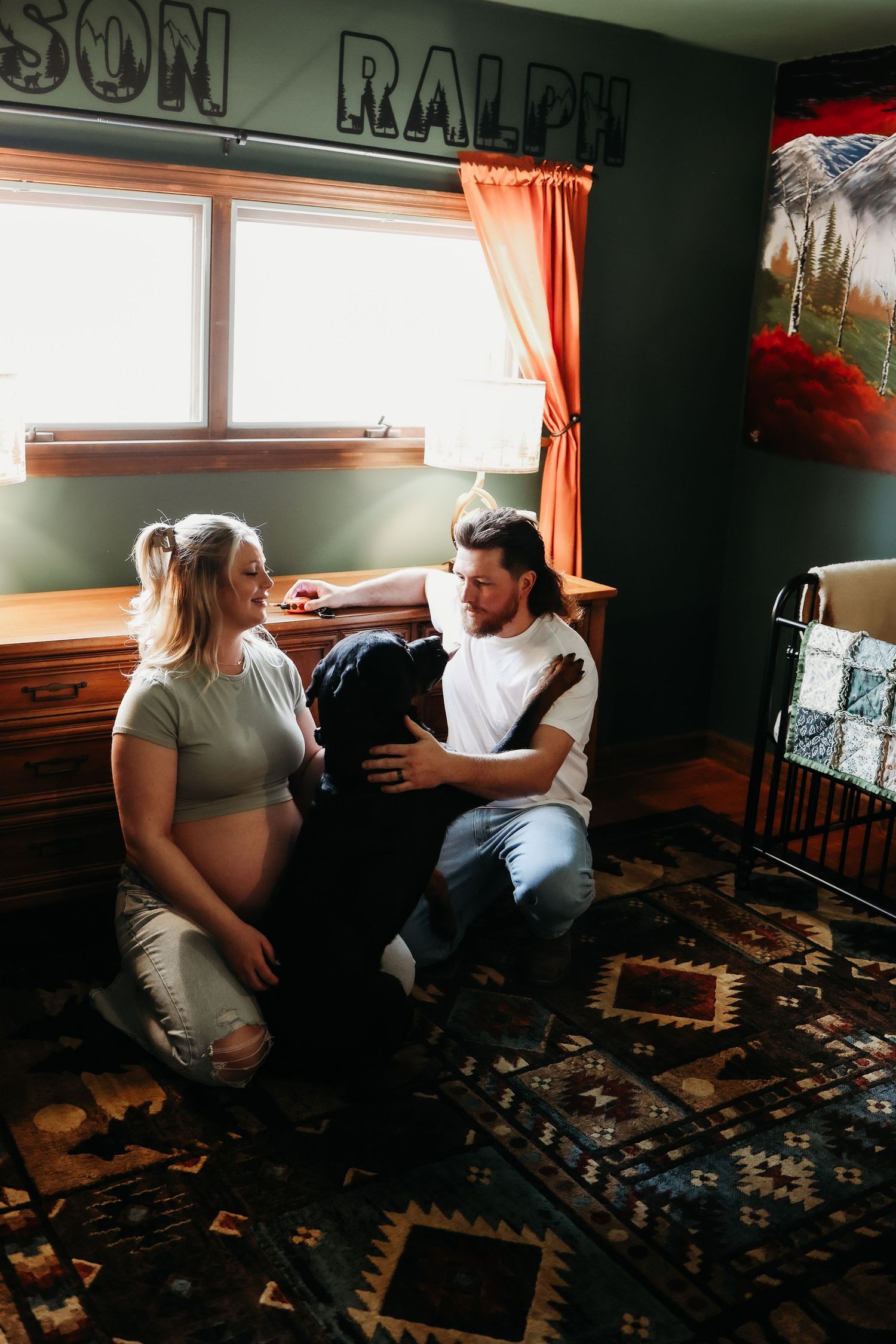 Couple sitting on patterned carpet in room with dark walls and orange curtains.