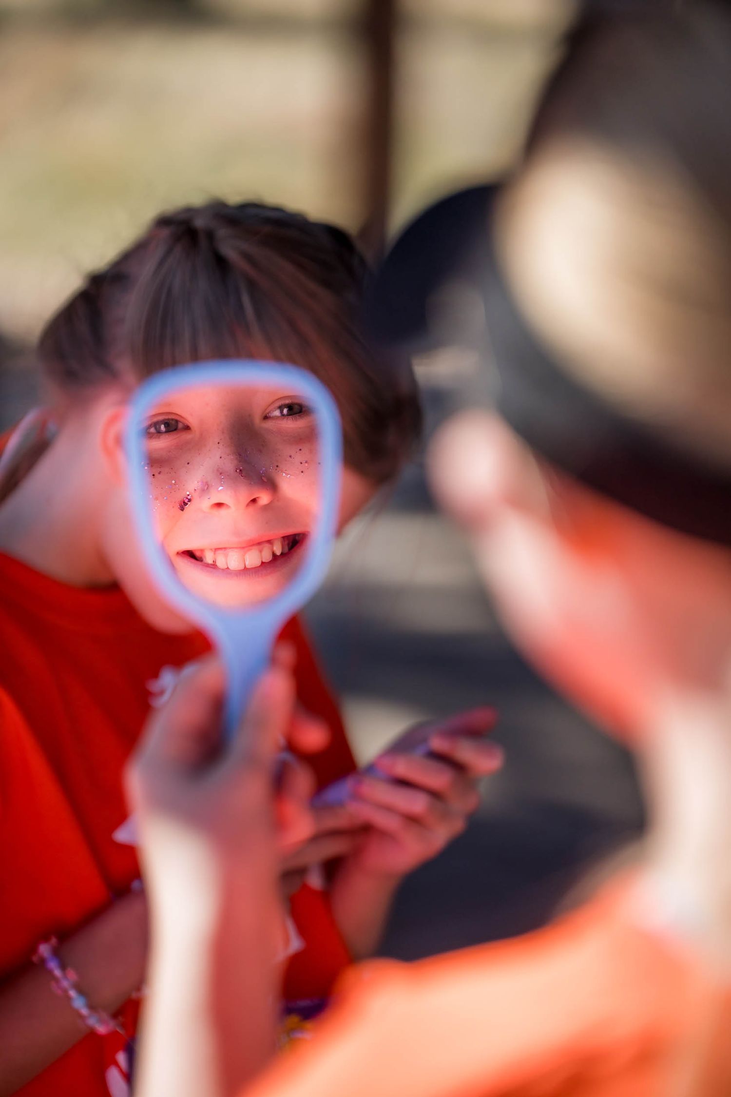 A person illuminated by blue light holds a device while smiling.