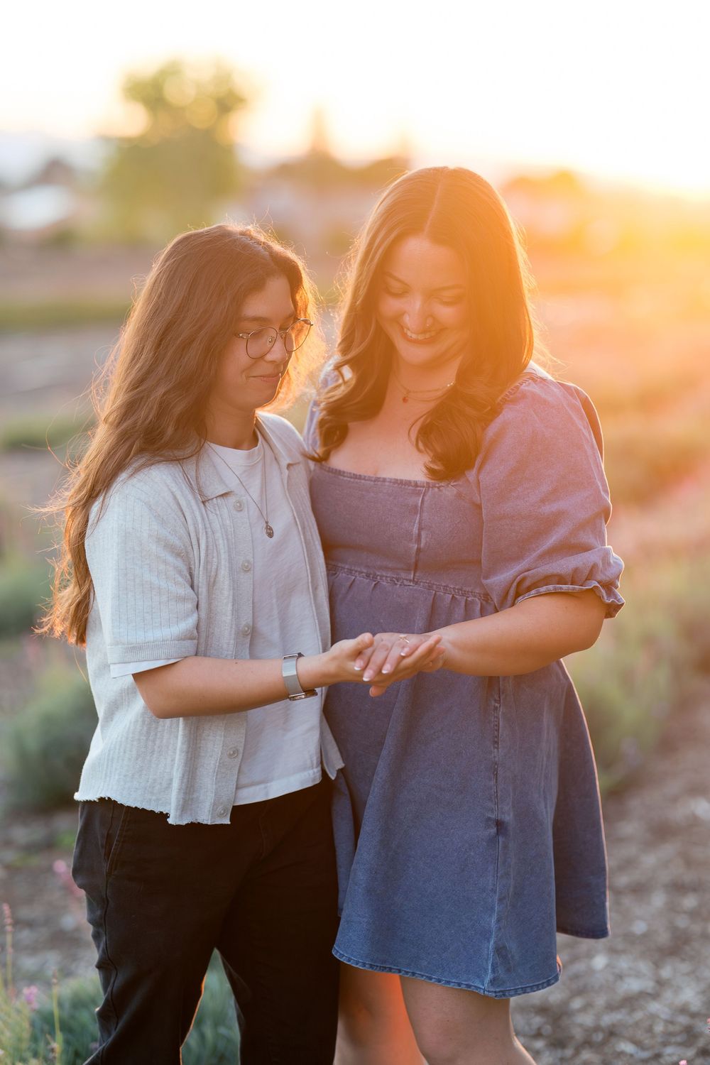 Two friends share joyful laughter together during sunset in a natural outdoor setting.