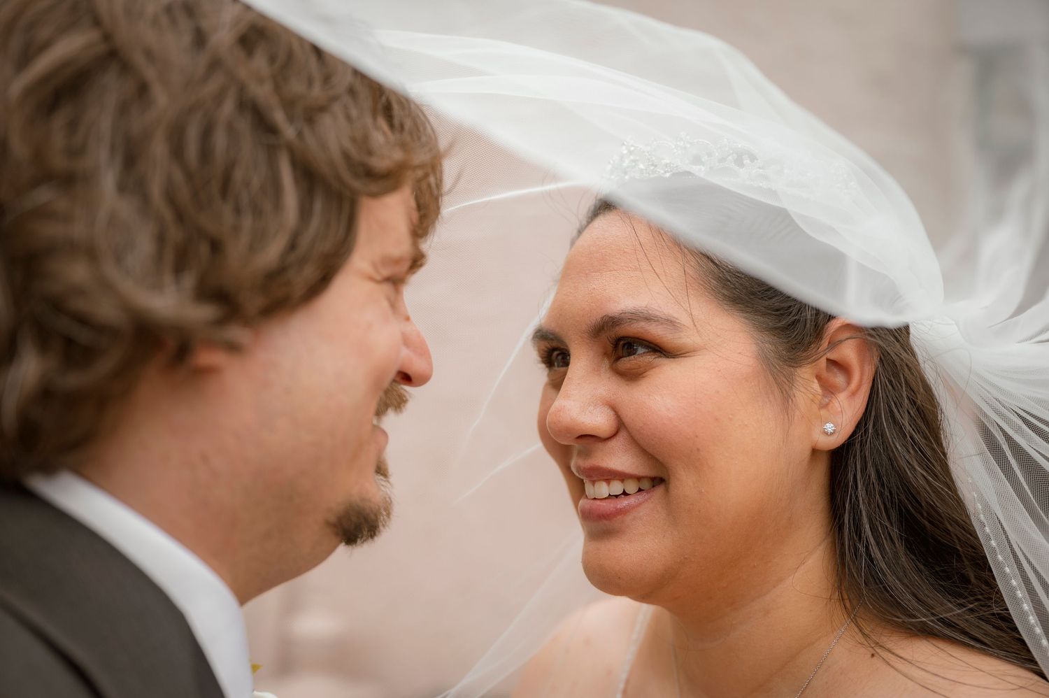 Newlyweds walking together by gazebo with bridal party in burgundy attire.