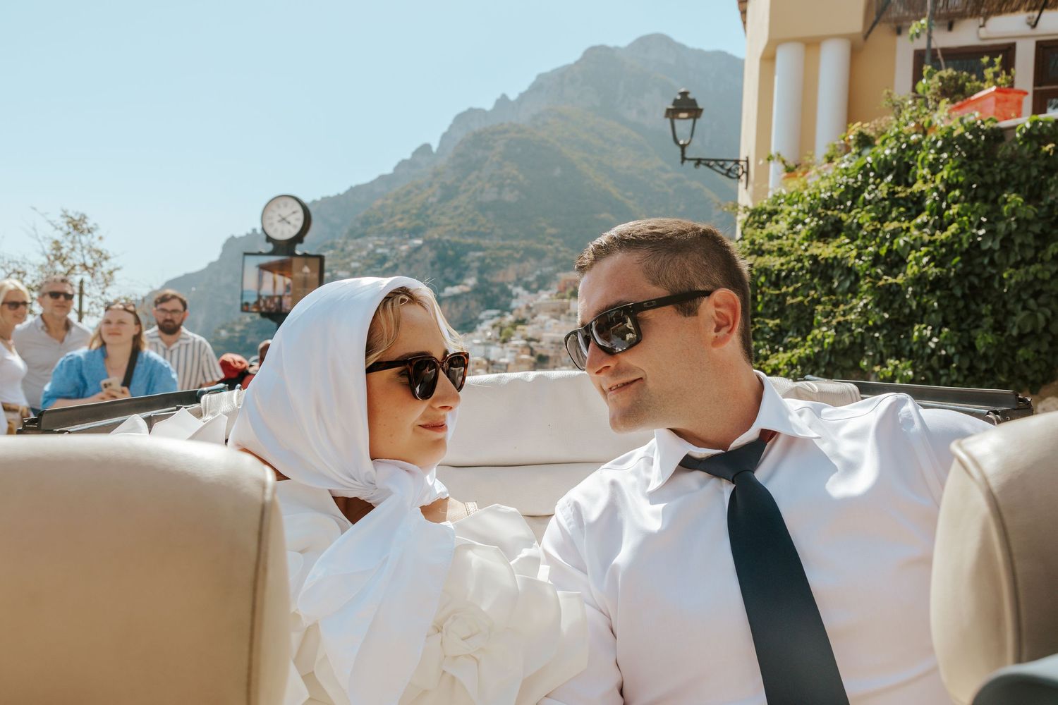 italy elopement in a vintage car with positano behind them as they drive along the Amalfi Coast