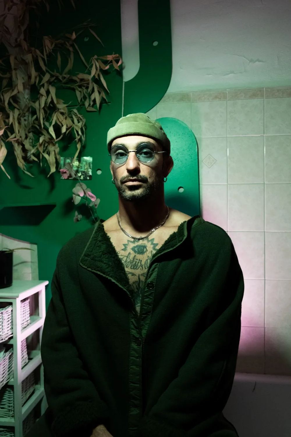Portrait d’un homme assis dans une pièce à la lumière verte, regard tourné vers l’objectif.