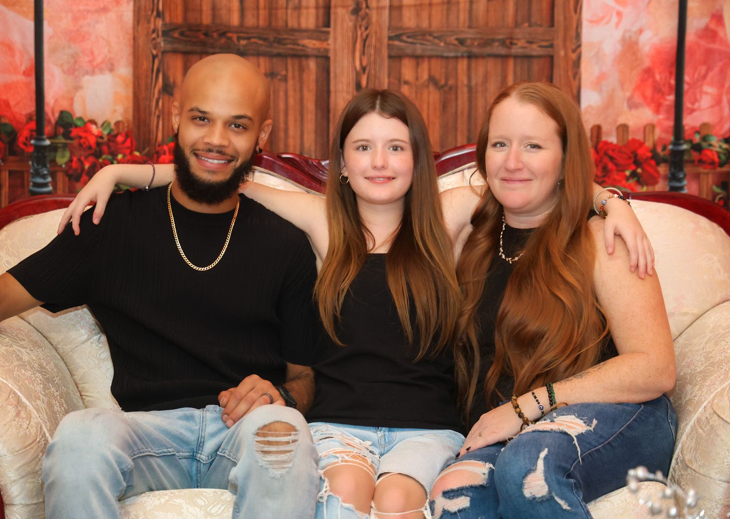 Group photo session with people sitting on white furniture against a pink backdrop with decorative elements.