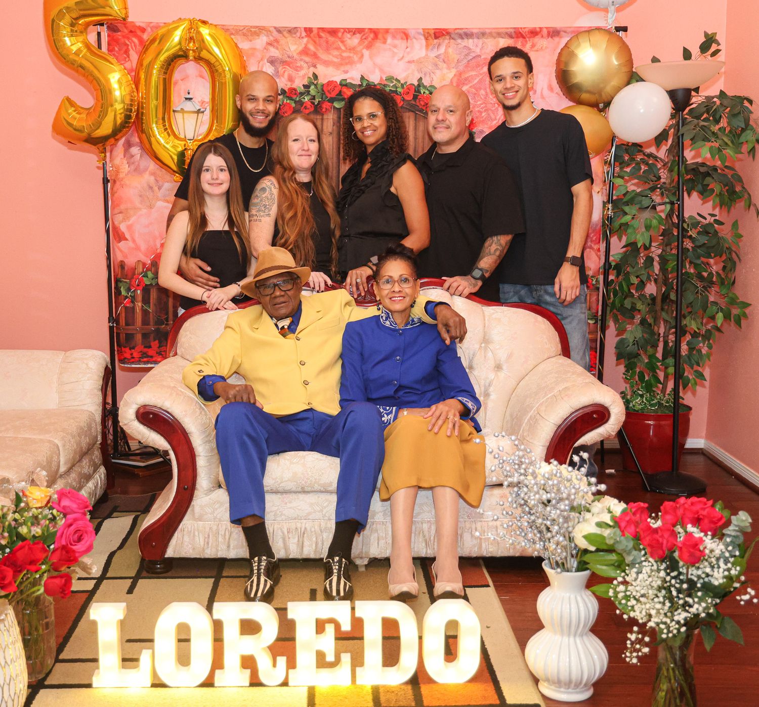 Family gathering with decorative elements and text overlay against coral-colored background.