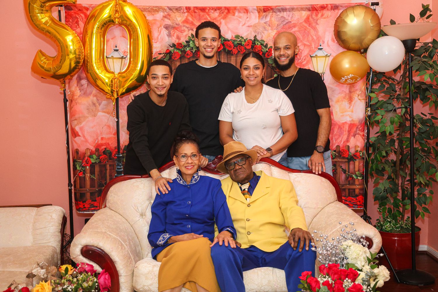 Intimate 50th birthday portrait with gold number balloons and pink backdrop.
