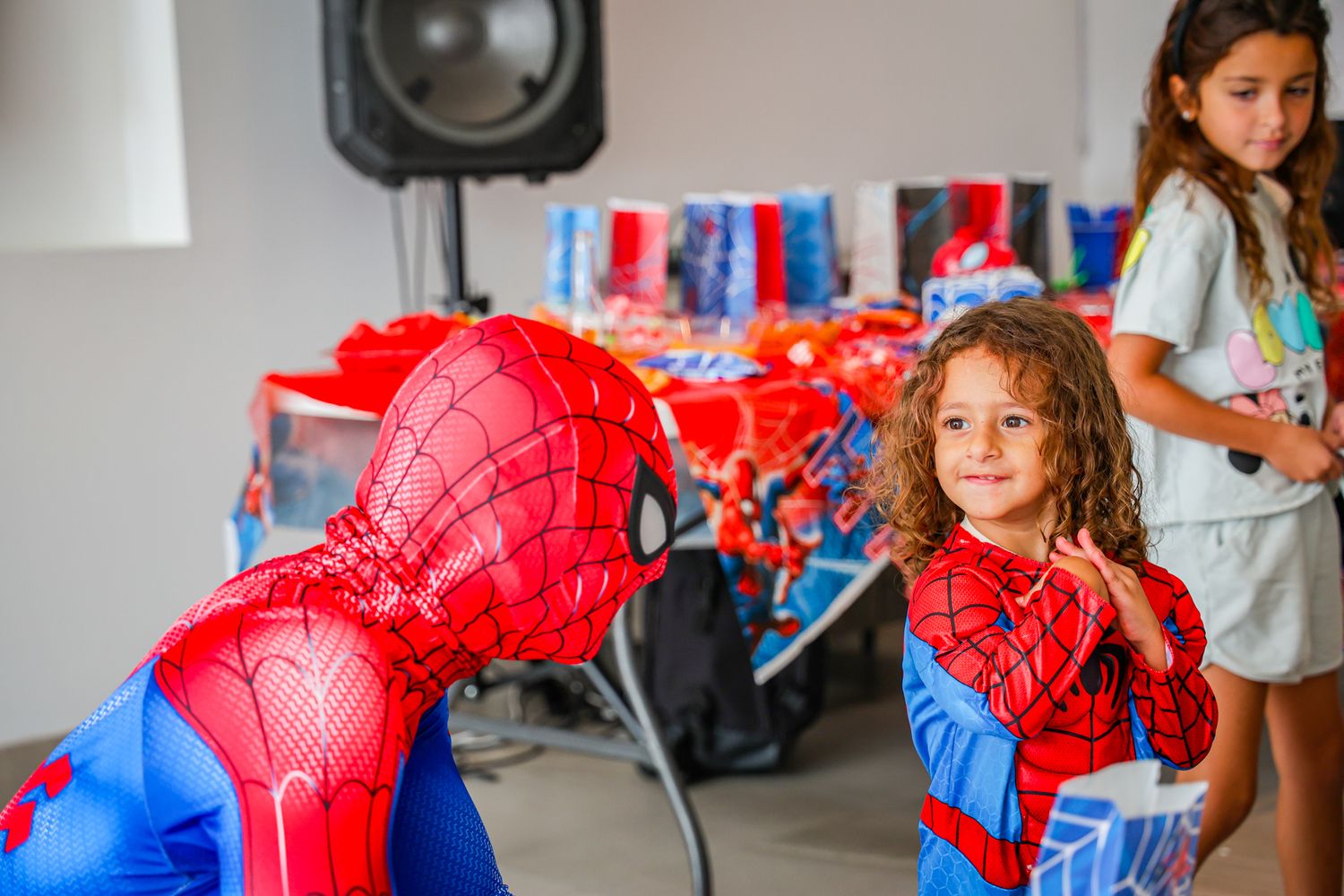 Spider-Man character interacting with party guests during an indoor celebration.