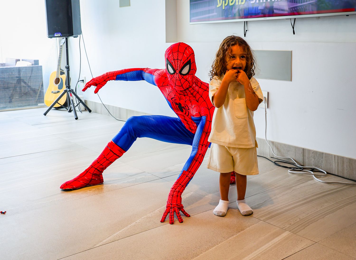 Spider-Man performer striking dynamic poses during an indoor entertainment event.