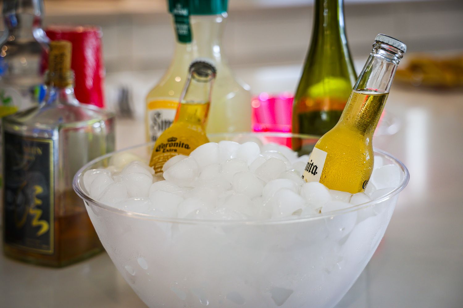 Assorted glass bottles and beverages chilling in ice buckets at a party or event.