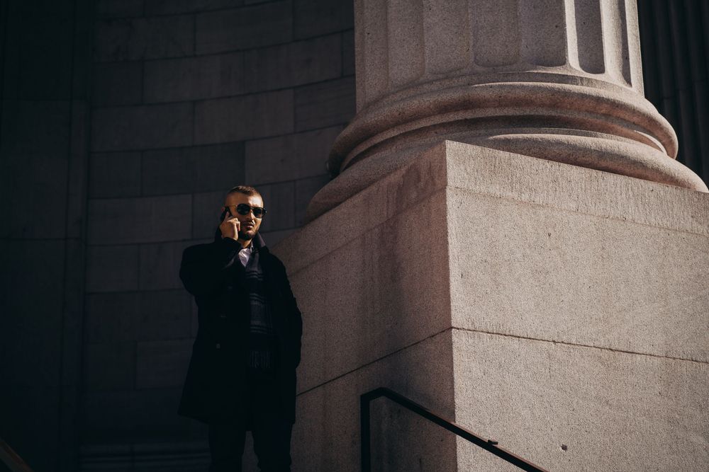 Urban fashion portrait against a stone column in dramatic lighting. Mtlshutter photography