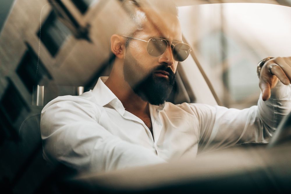 Close-up shot through car window of man in white shirt adjusting sunglasses. Mtlshutter photography