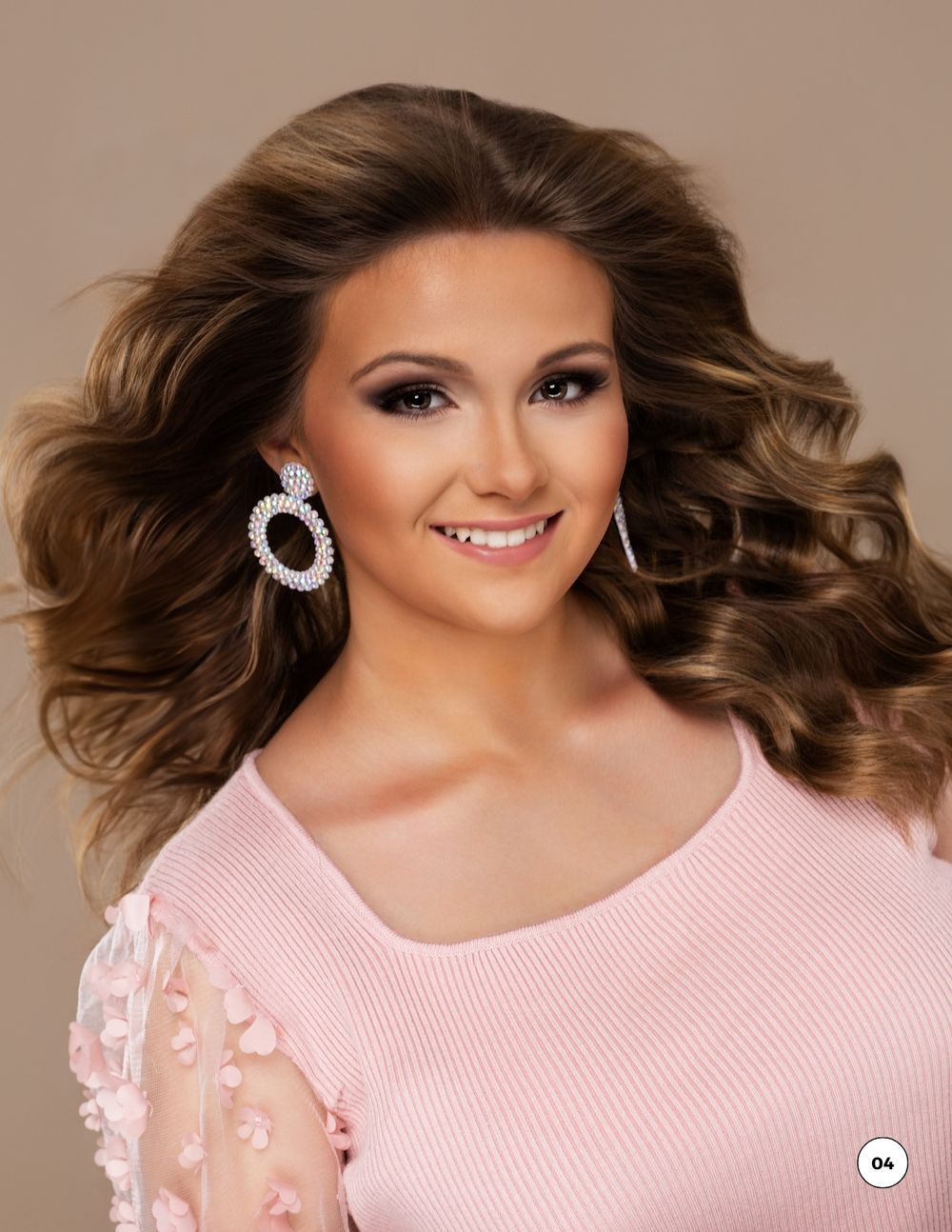 Portrait in pink sweater with sheer sleeves showcasing pageant-style hair and diamond hoop earrings. Kentucky pageant headshot photographer