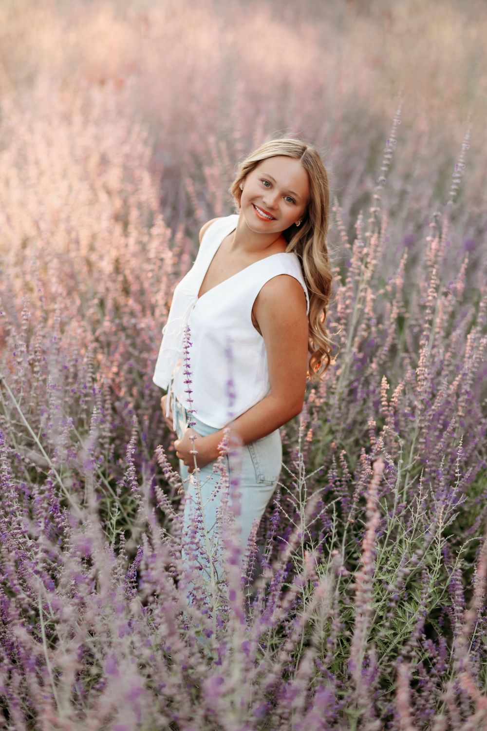 Senior Portrait in lavender field with person wearing white dress at sunset.