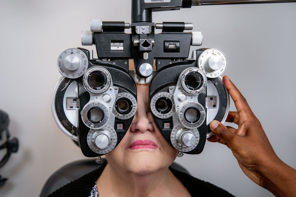 Patient undergoing vision test with phoropter during eye examination at optometry clinic.