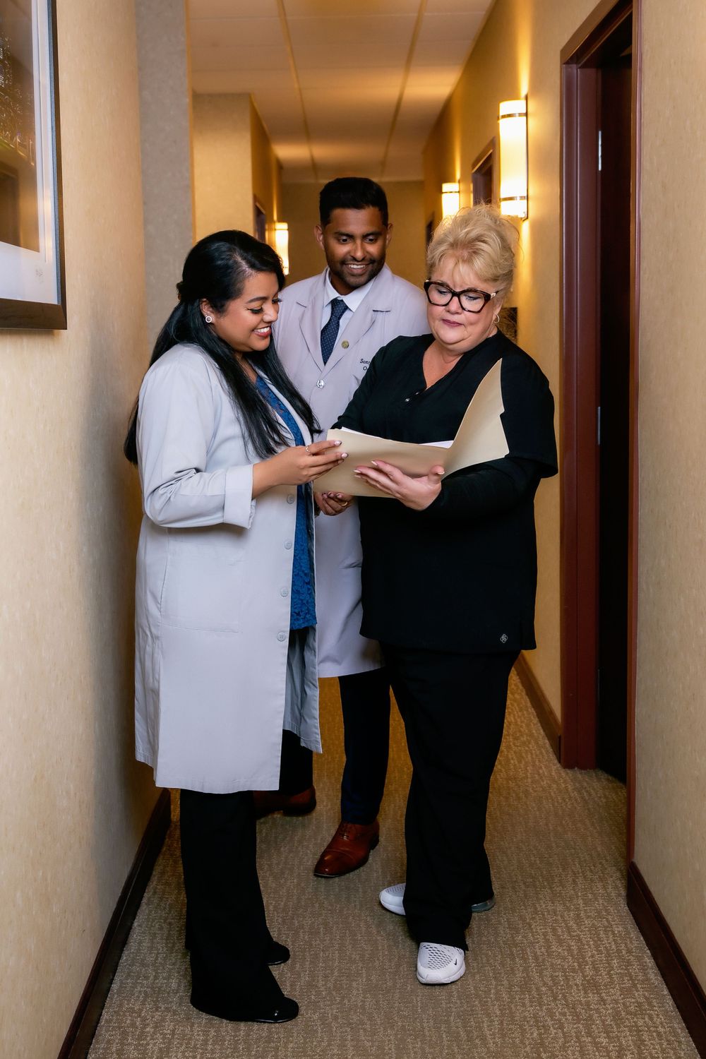 Medical professionals reviewing patient charts in office hallway.