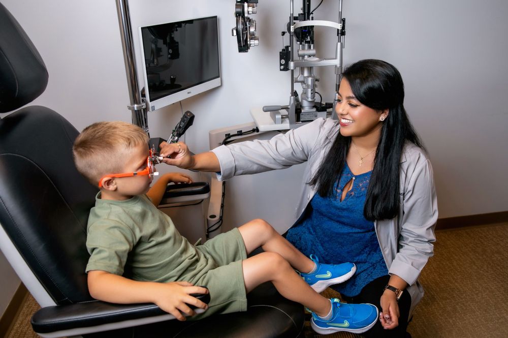 Eye care professional examining young patient during pediatric vision checkup.