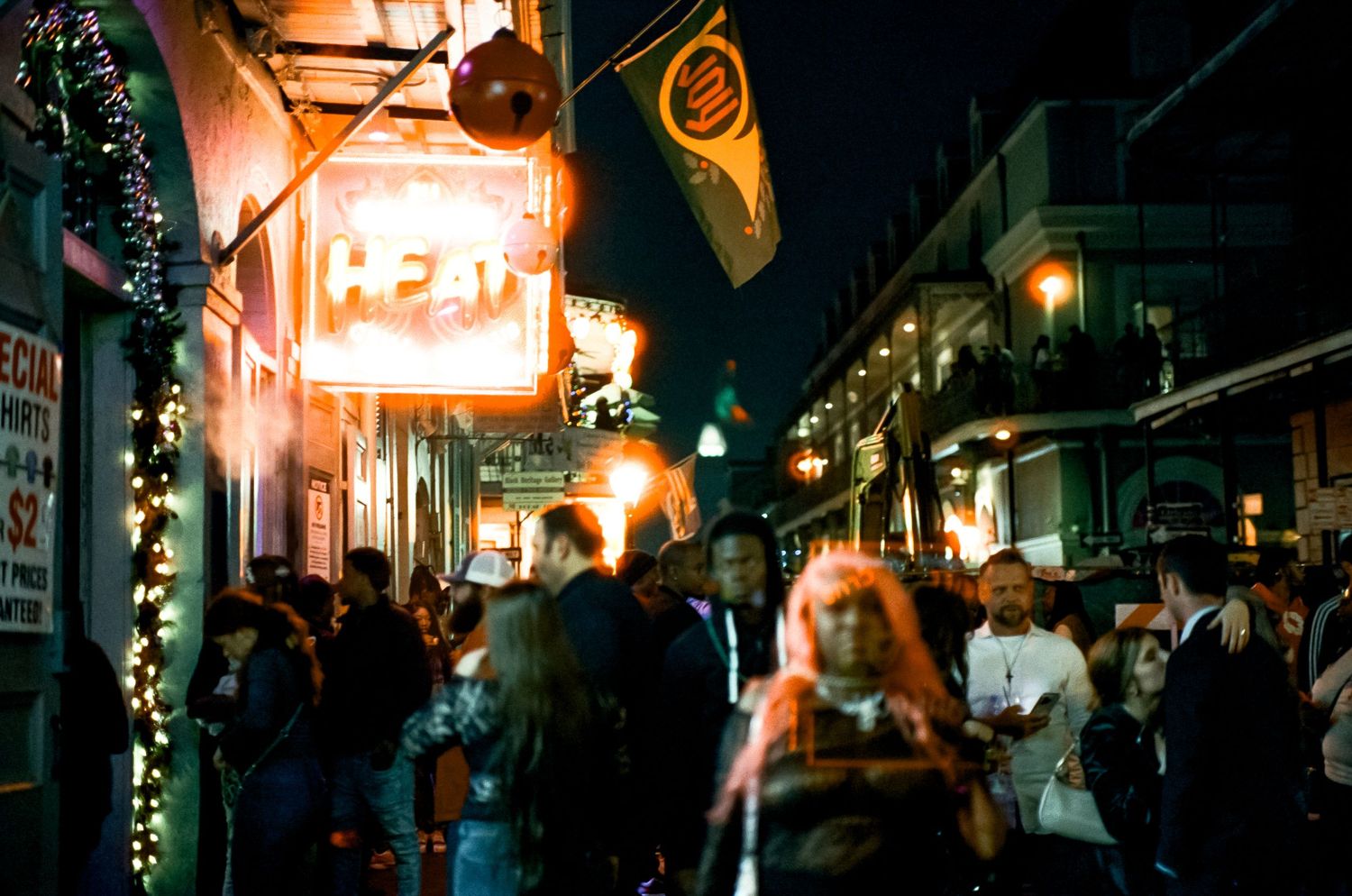 Crowded nighttime street scene with neon signs and holiday decorations in an entertainment district.