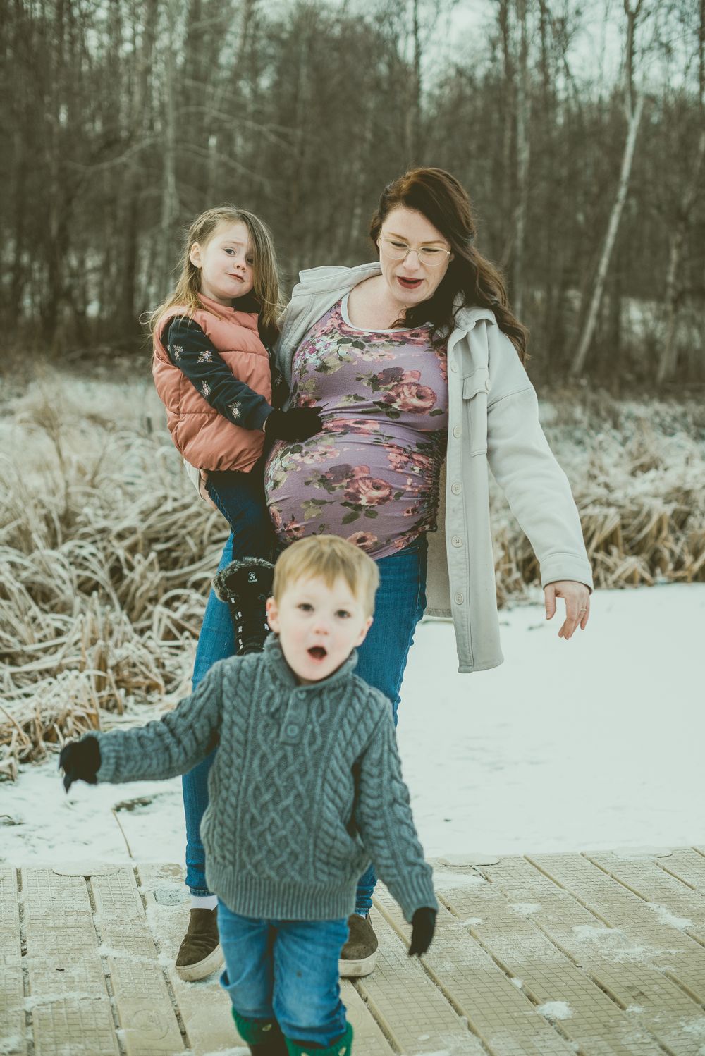 A joyful winter moment captured on a snowy path with family members showing playful expressions and warm clothing.