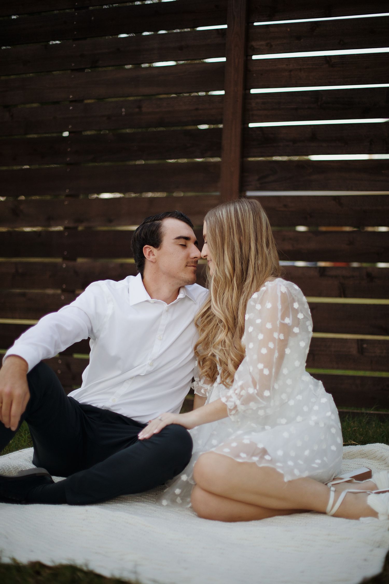 Couple touching noses on picnic blanket.
