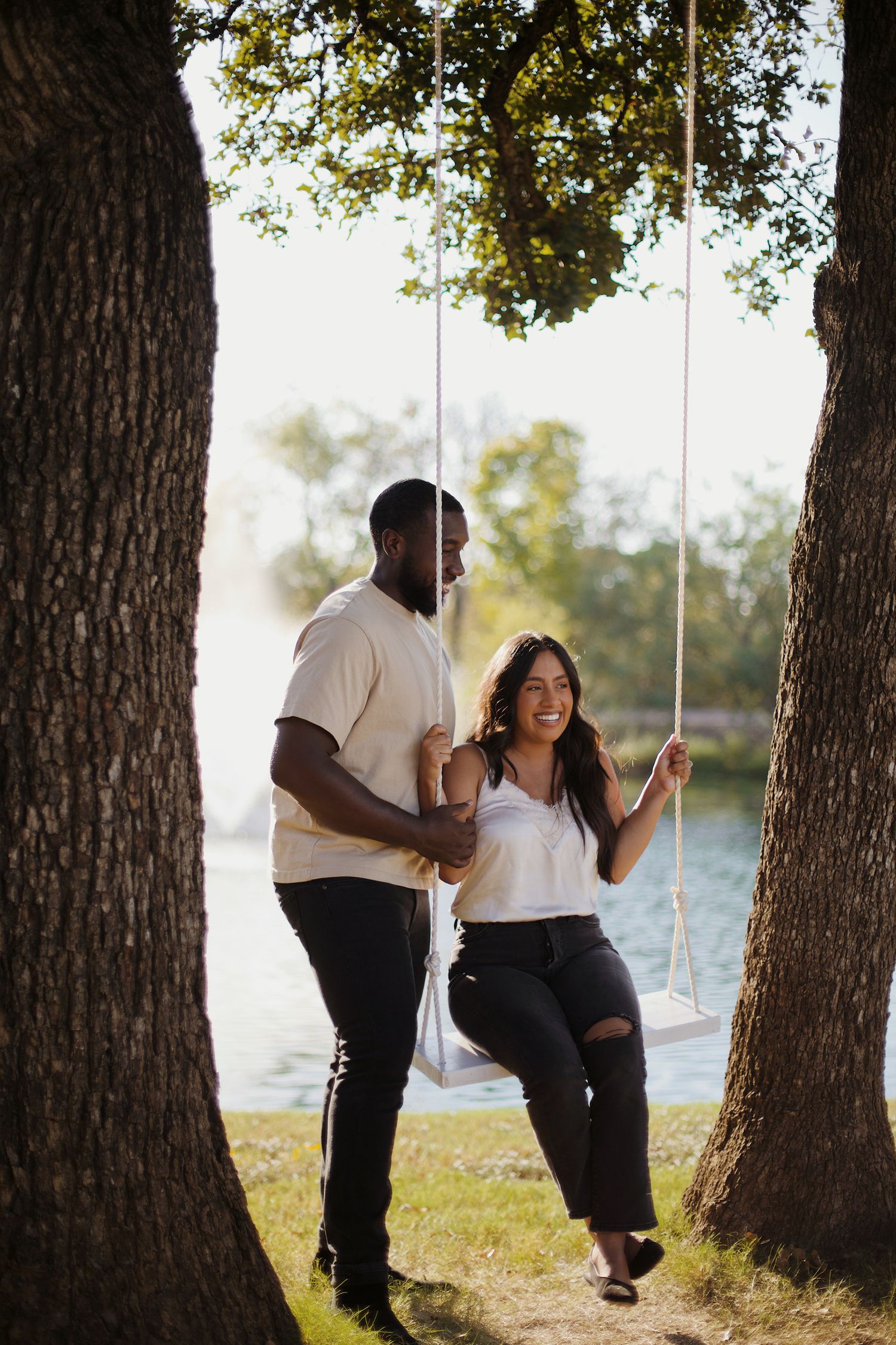 Cute couple swinging on a swing near the pond.