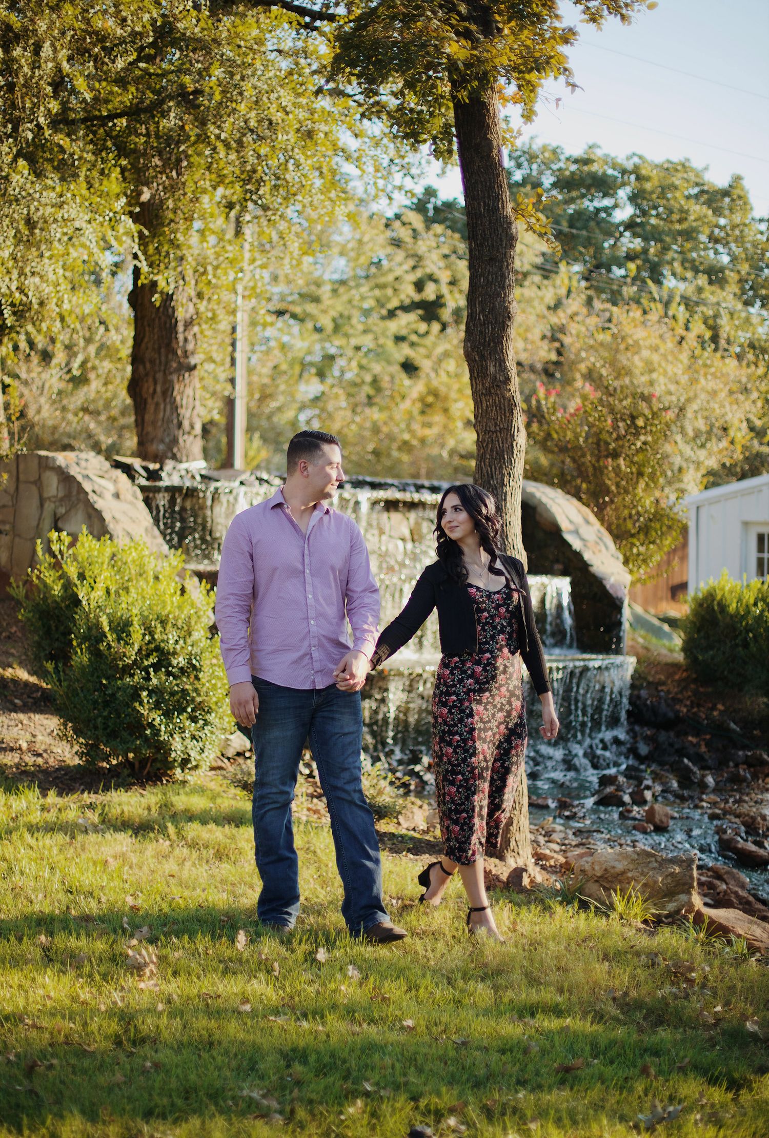 Couple walking along a river near a waterfall.