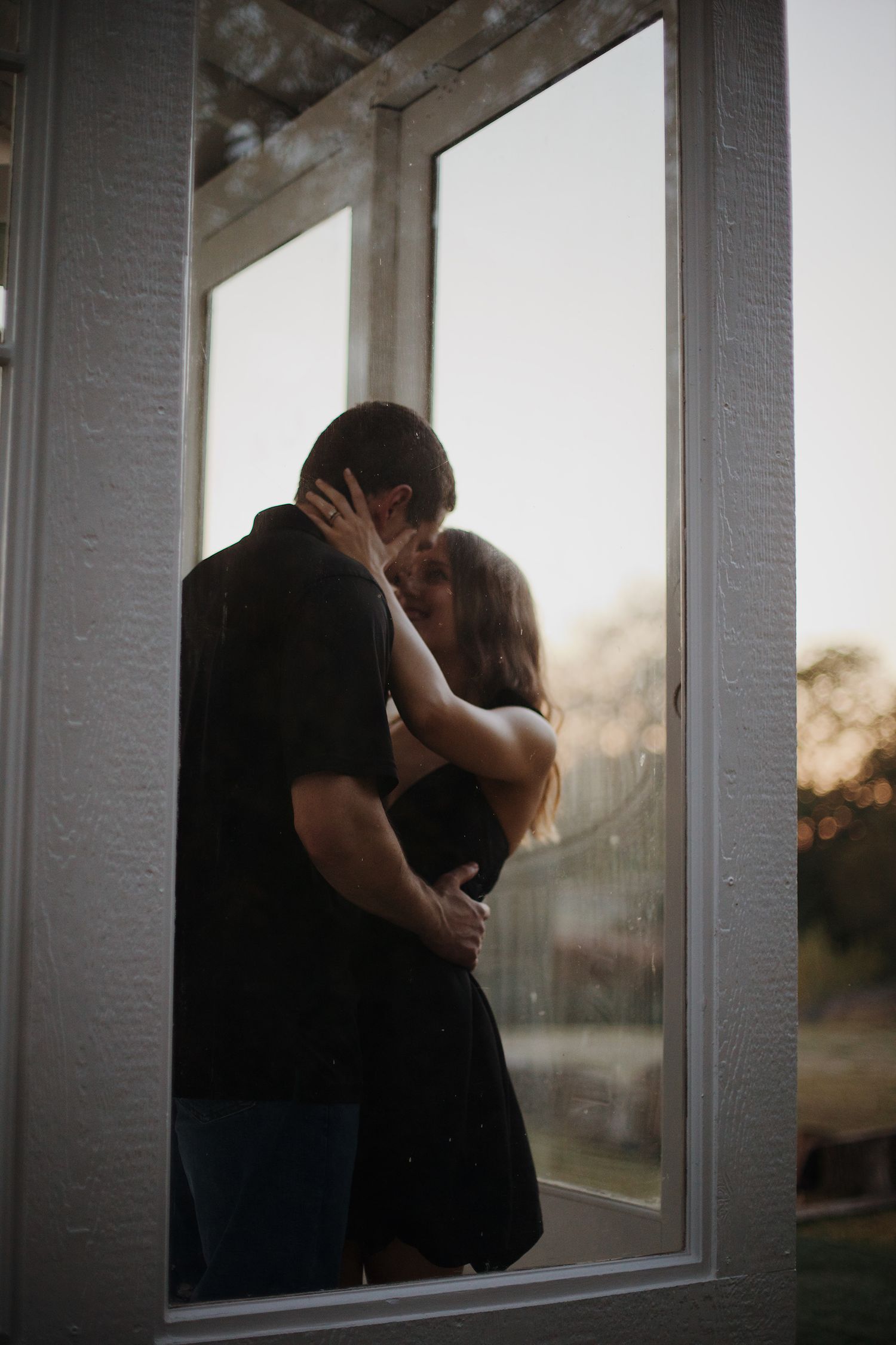 Engaged couple holding each other through window.