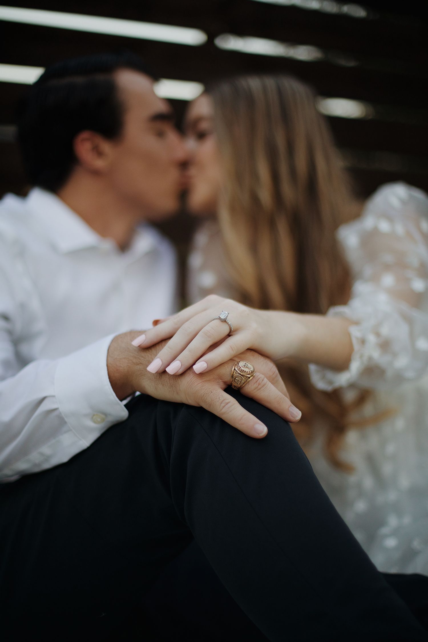 Engaged couple kissing with the focus on the rings.