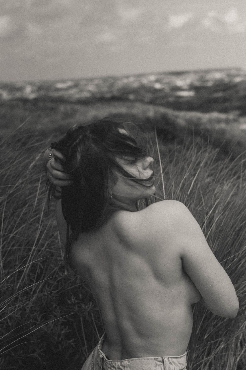 Black and white artistic photo showing bare back against natural landscape.
