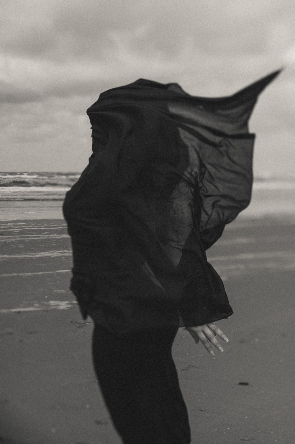 Artistic black and white photo of fabric flowing in the wind on a beach.