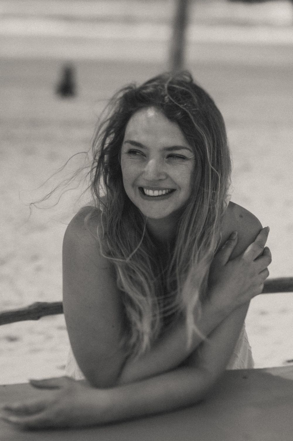 Black and white portrait series showing carefree laughter and expressions on a beach.